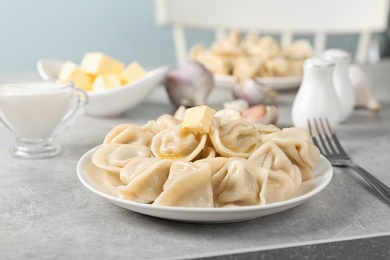 Photo of Tasty dumplings with butter on light grey table against blurred background