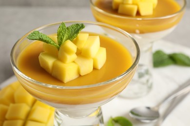 Photo of Delicious panna cotta with mango coulis, fresh fruit pieces and mint in dessert bowl, closeup