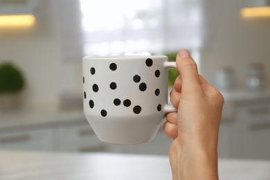 Photo of Woman holding elegant cup in kitchen, closeup