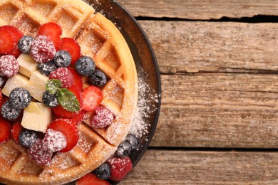 Tasty Belgian waffle with fresh berries, cheese and powdered sugar on wooden table, top view. Space for text