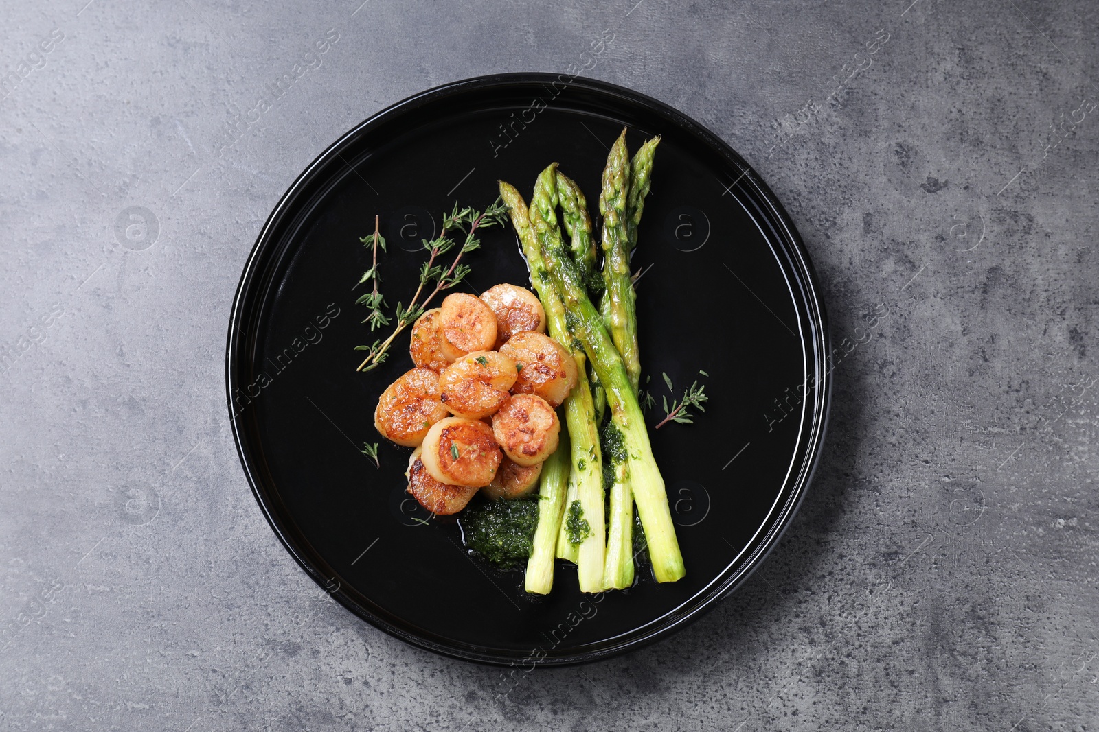Photo of Delicious fried scallops with asparagus and thyme on grey table, top view