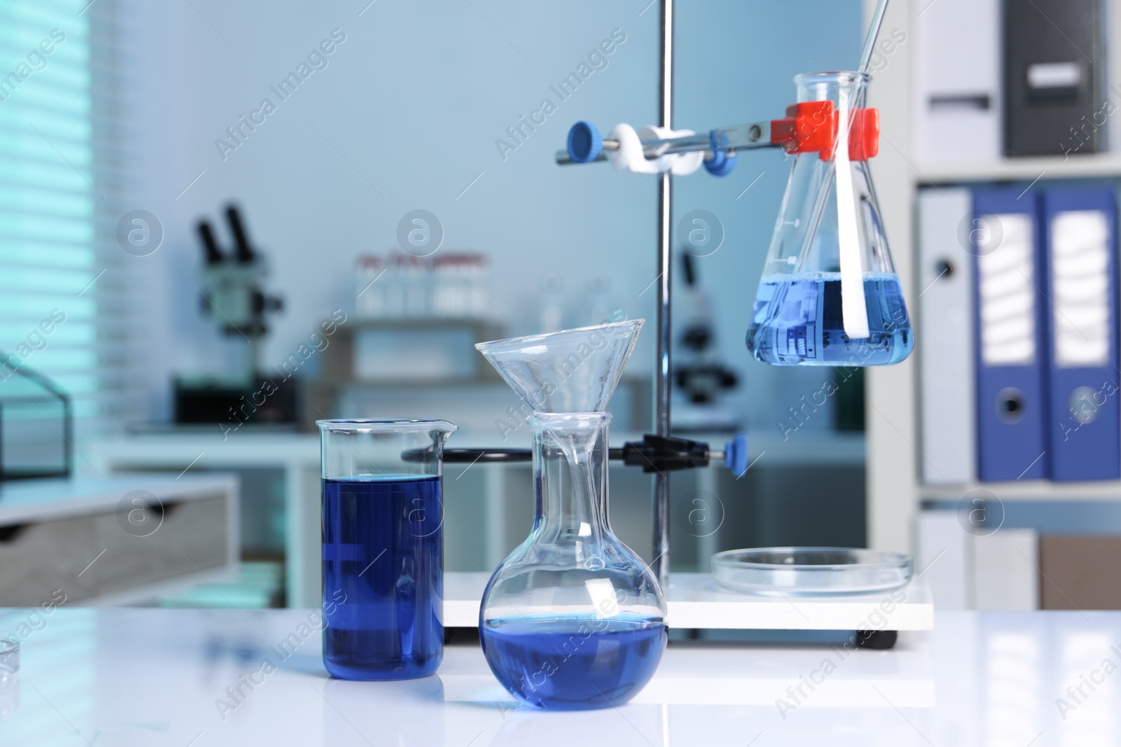 Photo of Laboratory analysis. Flasks and beaker with blue liquid on white table indoors