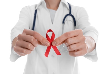 Doctor holding red awareness ribbon on white background, closeup. World AIDS disease day