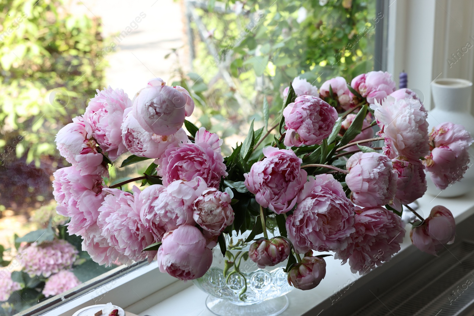 Photo of Beautiful pink peonies in vase on window sill. Interior design