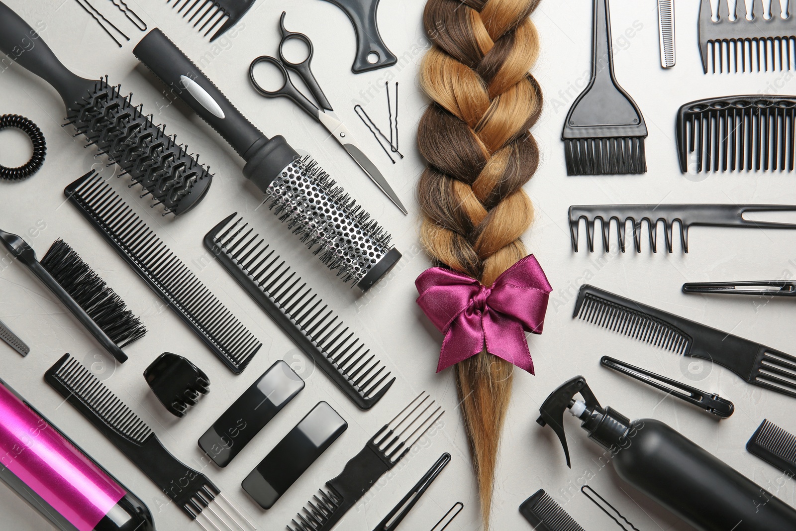 Photo of Flat lay composition with braid and hairdresser's tools on gray background