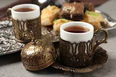 Photo of Tea and baklava served in vintage tea set on grey table, closeup
