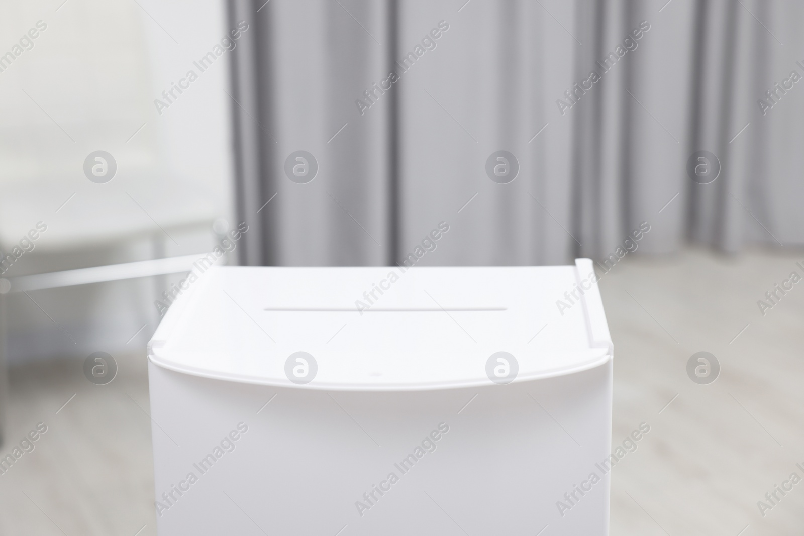 Photo of White ballot box on blurred background, closeup. Space for text