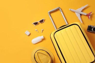 Photo of Flat lay composition with suitcase and travel accessories on yellow background. Summer vacation