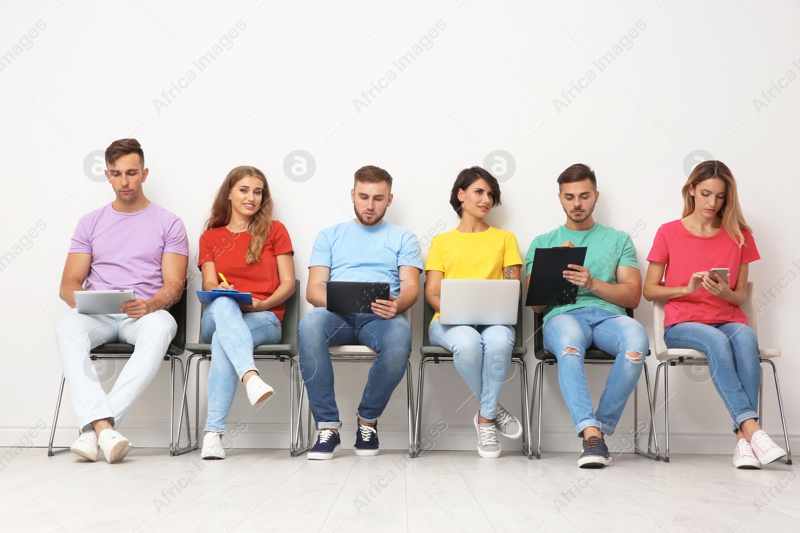 Photo of Group of young people waiting for job interview near light wall