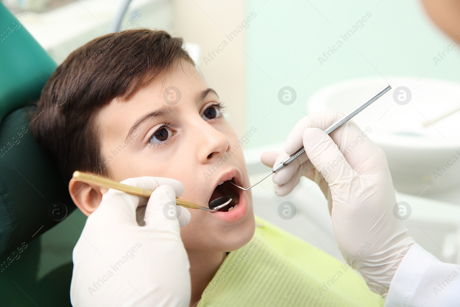 Photo of Professional dentist working with little patient in modern clinic