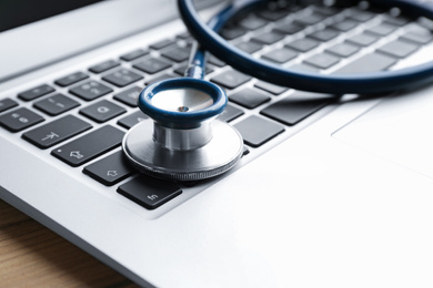 Photo of Laptop and stethoscope on table, closeup. Concept of technical support