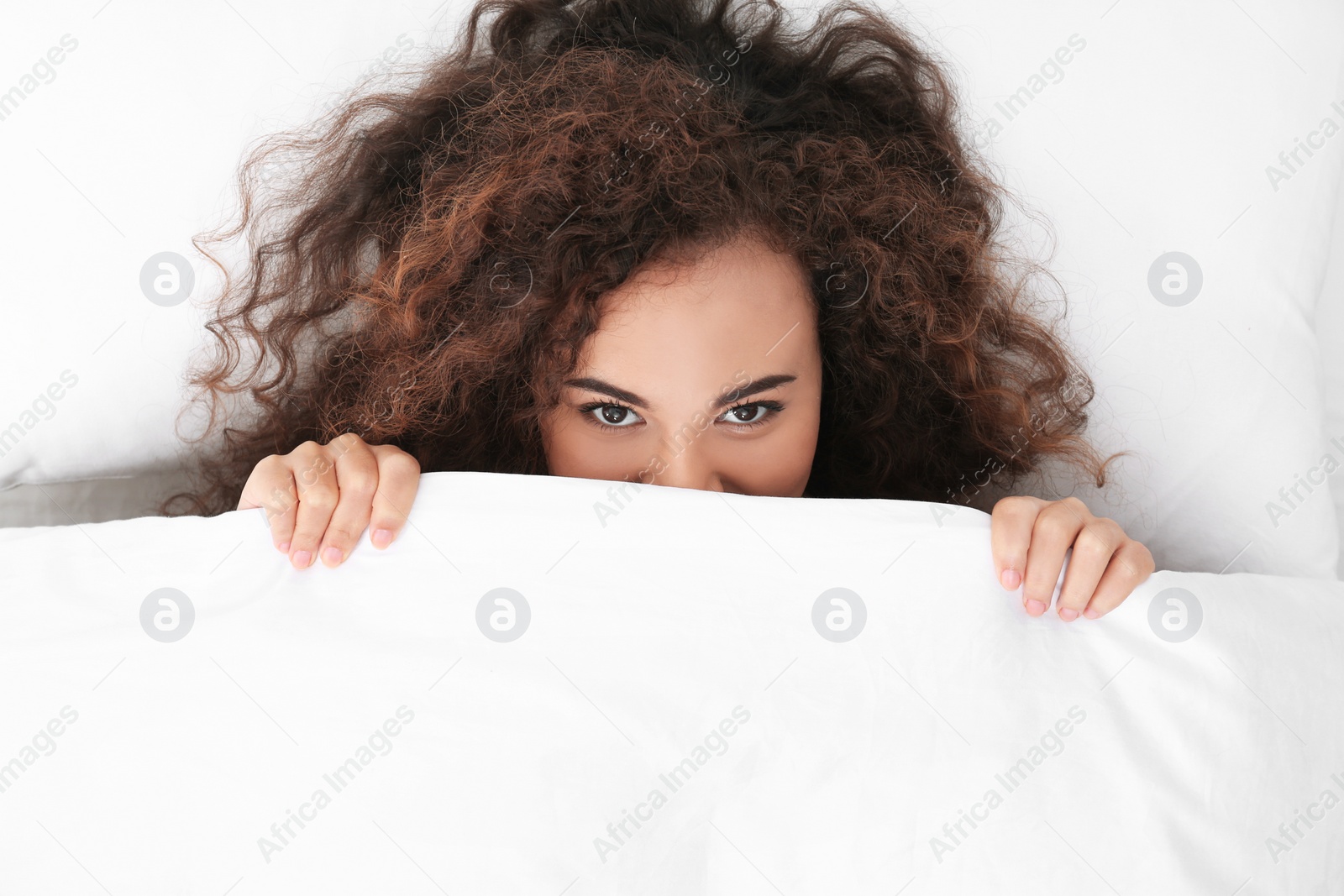 Photo of Young African-American woman lying under blanket, top view. Bedtime