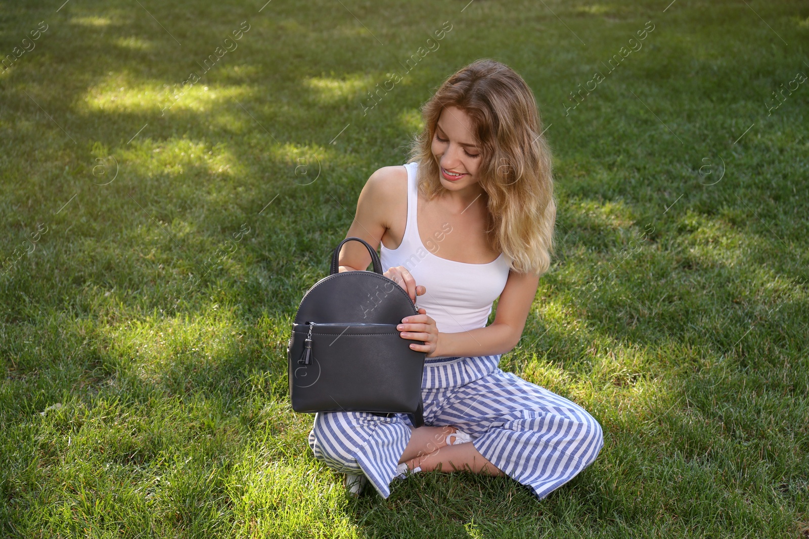 Photo of Young woman with stylish backpack in park