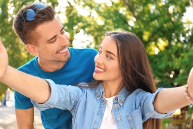 Photo of Young couple taking selfie outdoors on sunny day