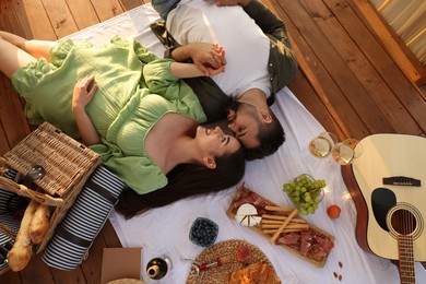 Photo of Romantic date. Beautiful couple resting on picnic blanket, top view