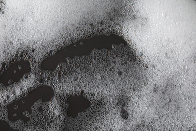 Photo of Fluffy bath foam on grey background, closeup view