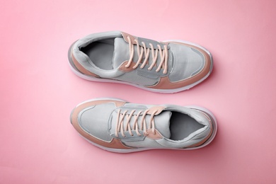 Pair of stylish sneakers on color background, top view