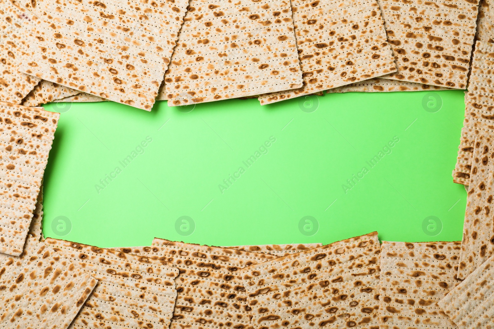 Photo of Frame of traditional matzos on green background, flat lay. Space for text