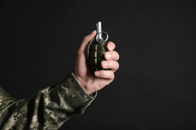 Soldier holding hand grenade on black background, closeup with space for text. Military service