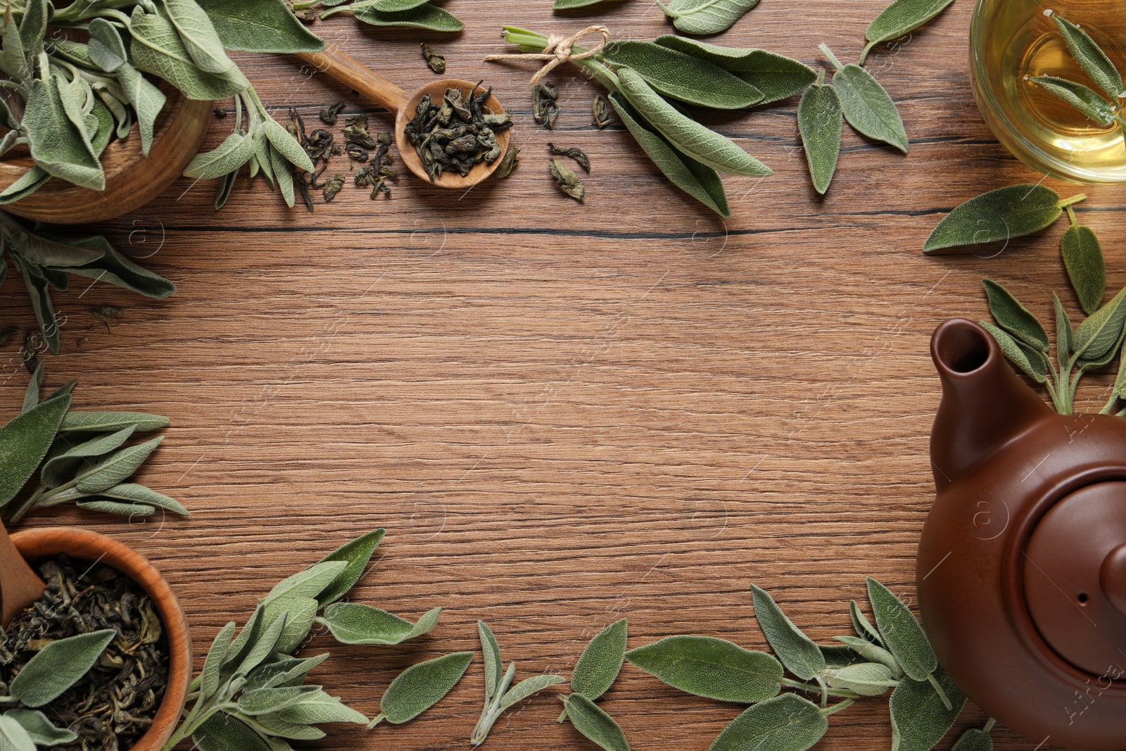 Photo of Flat lay composition with cup of sage tea, green leaves and teapot on wooden table. Space for text