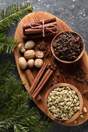 Photo of Different spices and fir branches on dark gray textured table, flat lay
