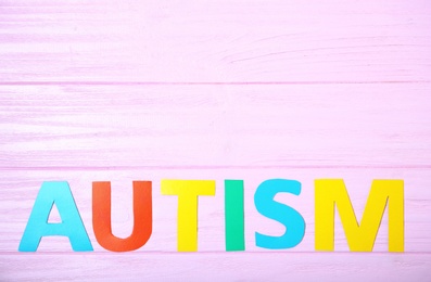 Photo of Word AUTISM on color background, top view