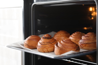 Open oven with tray of freshly baked buns, closeup