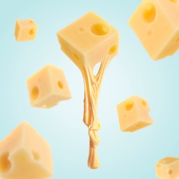 Pieces of cheese falling on light blue background