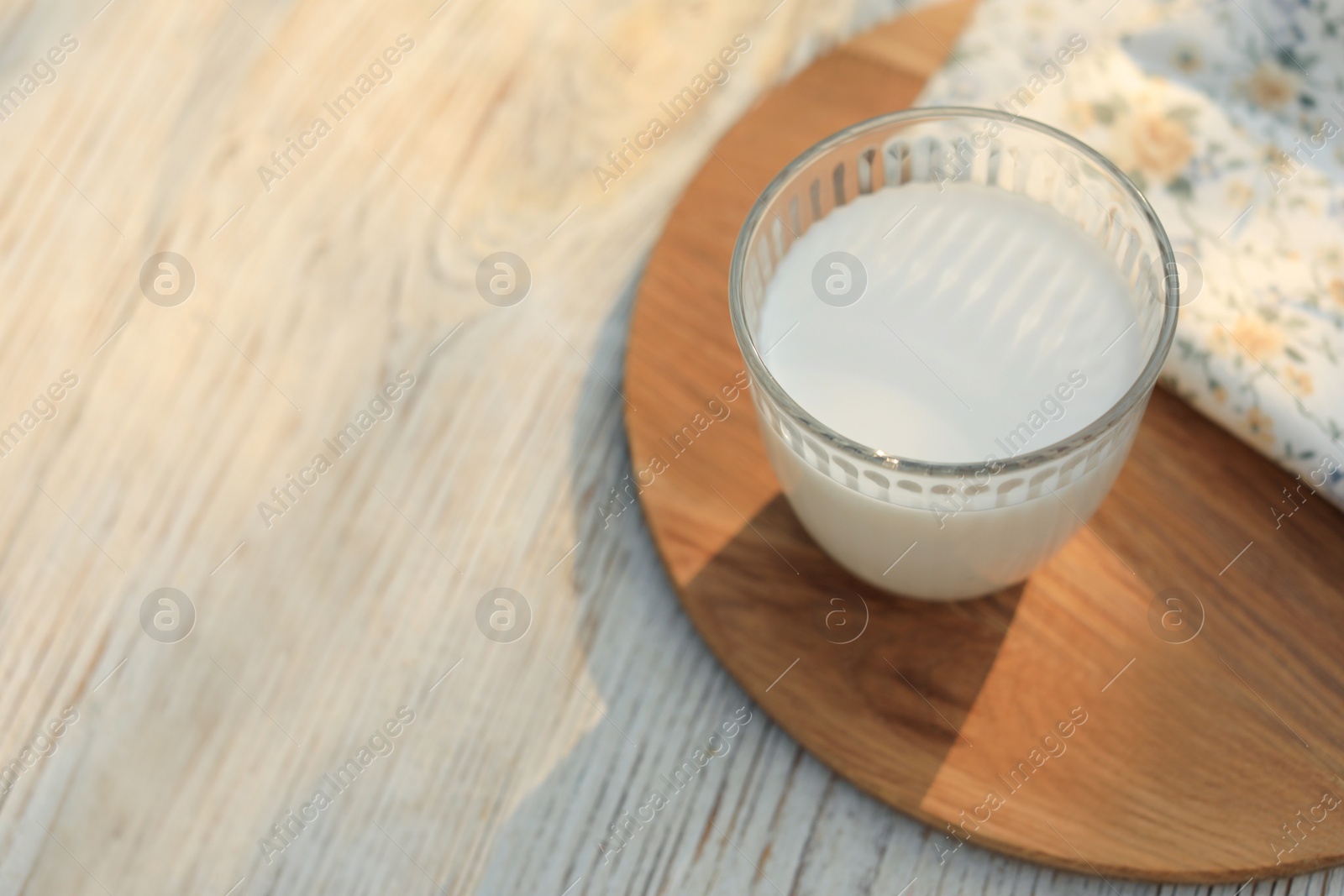 Photo of Glass of tasty fresh milk on white wooden table, above view. Space for text