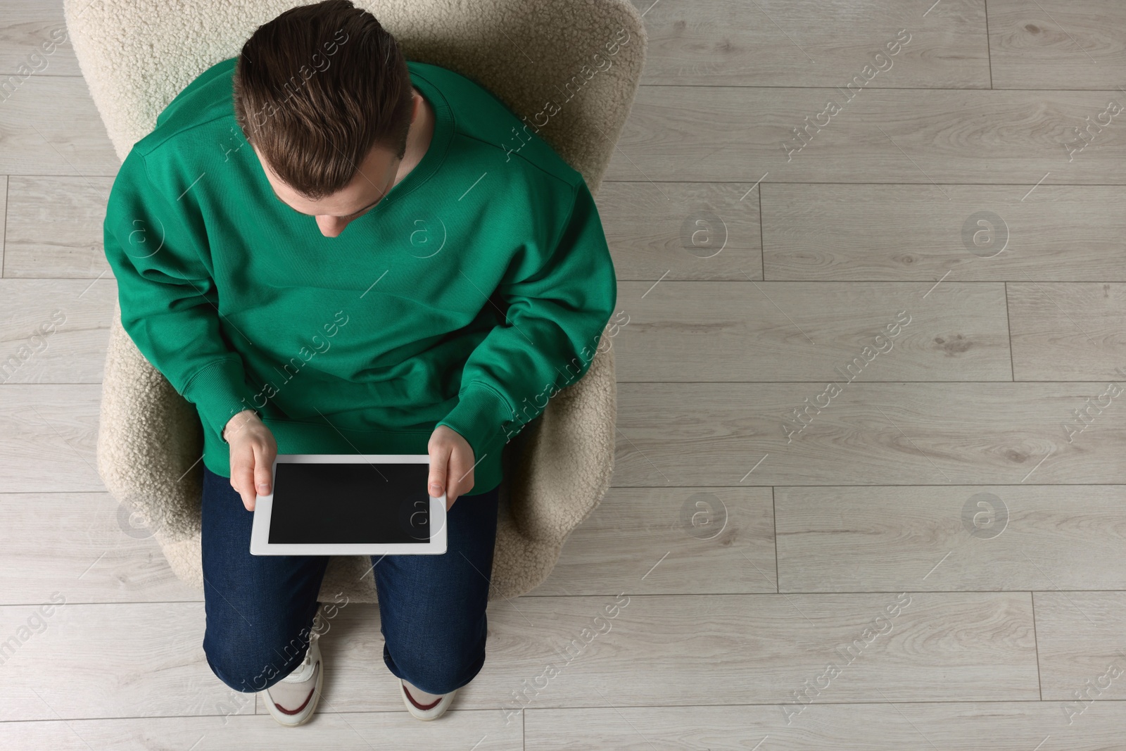 Photo of Man working with tablet in armchair, top view. Space for text