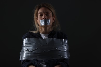 Woman taped up and taken hostage on dark background