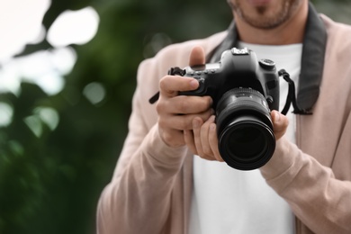 Photo of Male photographer with professional camera on blurred background. Space for text