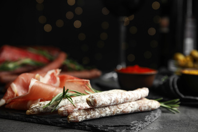 Photo of Delicious sausages and prosciutto on table. Space for text