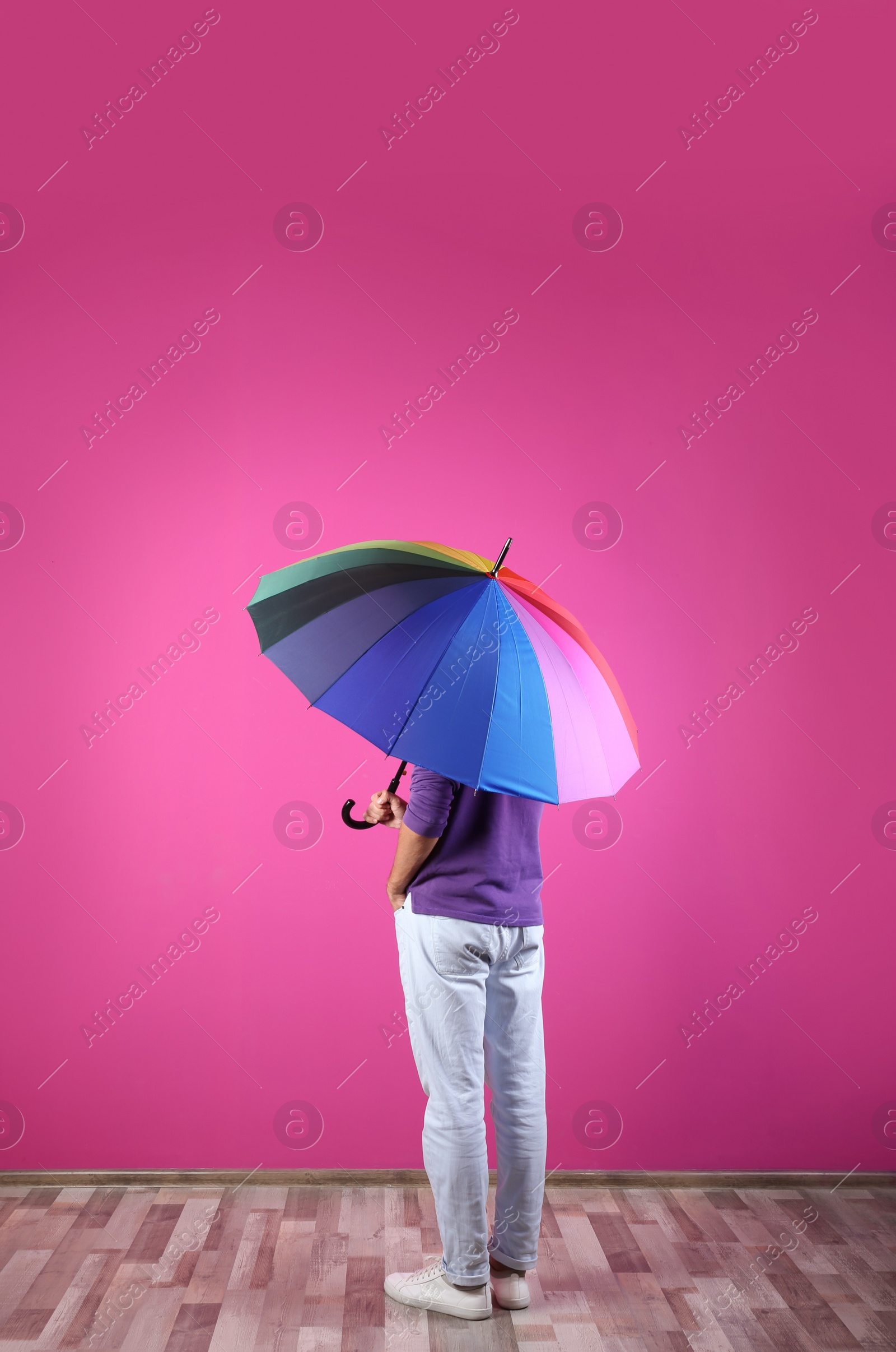 Photo of Man with rainbow umbrella near color wall