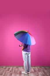 Man with rainbow umbrella near color wall