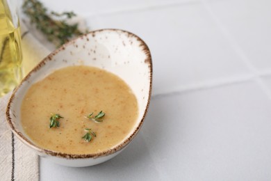 Photo of Delicious turkey gravy and thyme on white tiled table, closeup. Space for text