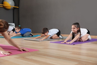 Cute little children and trainer doing physical exercise in school gym. Healthy lifestyle