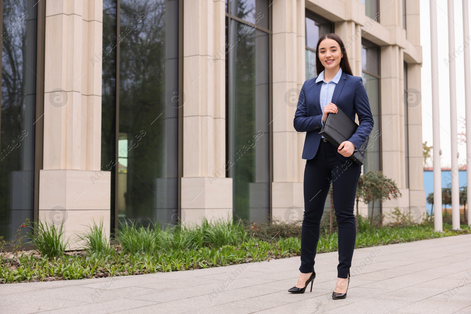 Photo of Female real estate agent with leather portfolio outdoors