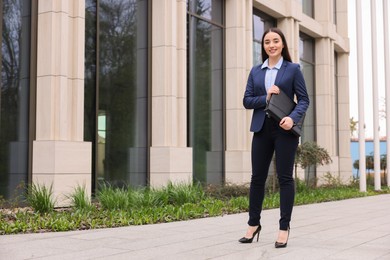 Female real estate agent with leather portfolio outdoors