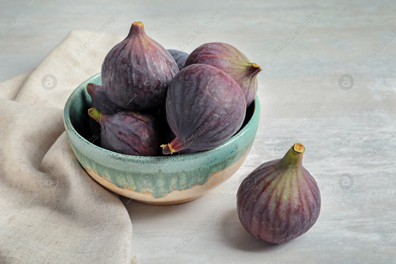 Photo of Bowl with fresh ripe figs on light background. Tropical fruit