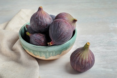 Bowl with fresh ripe figs on light background. Tropical fruit