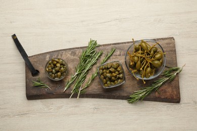 Photo of Delicious pickled capers and rosemary twigs on white wooden table, top view