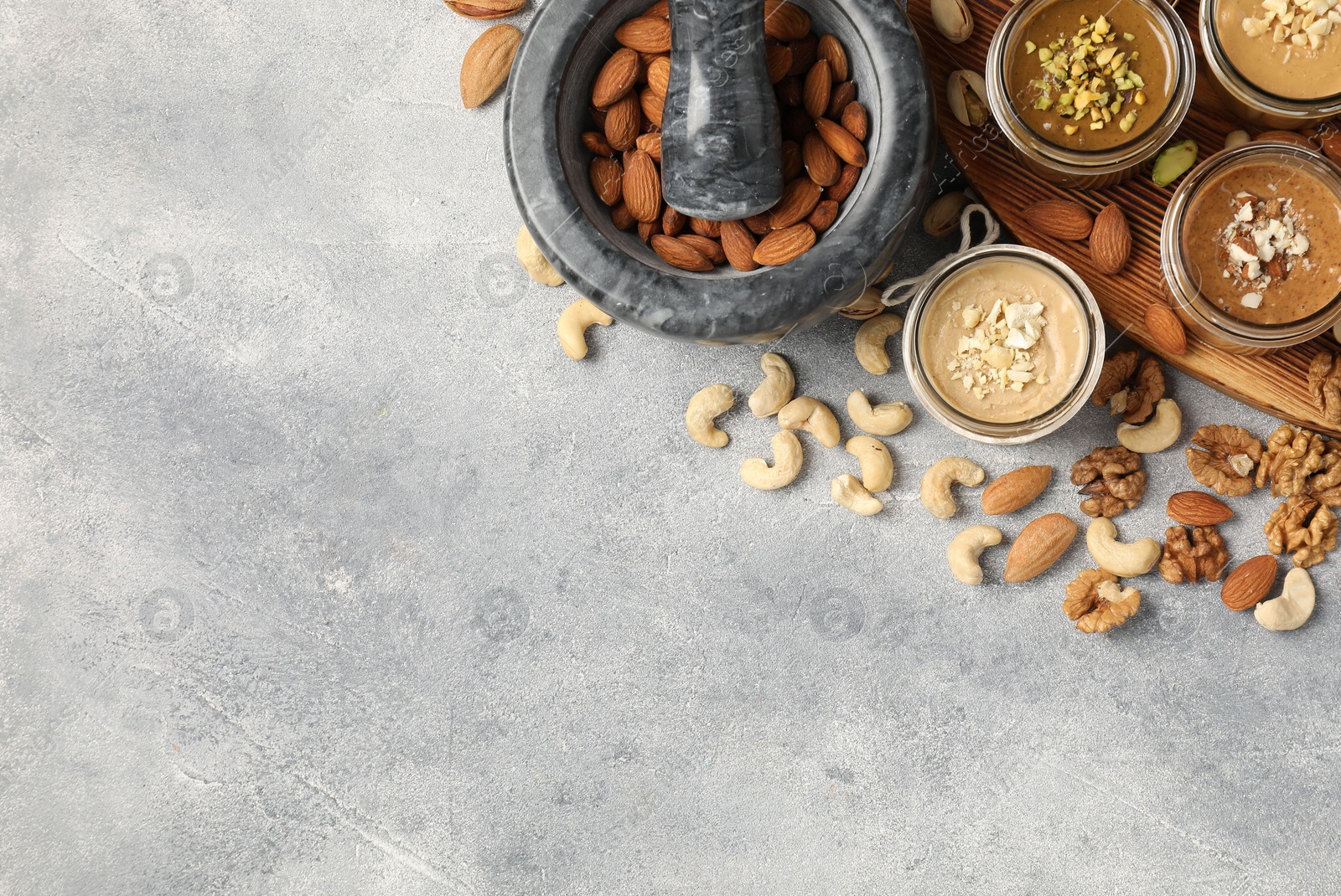 Photo of Making nut butters from different nuts. Flat lay composition with space for text on light grey table