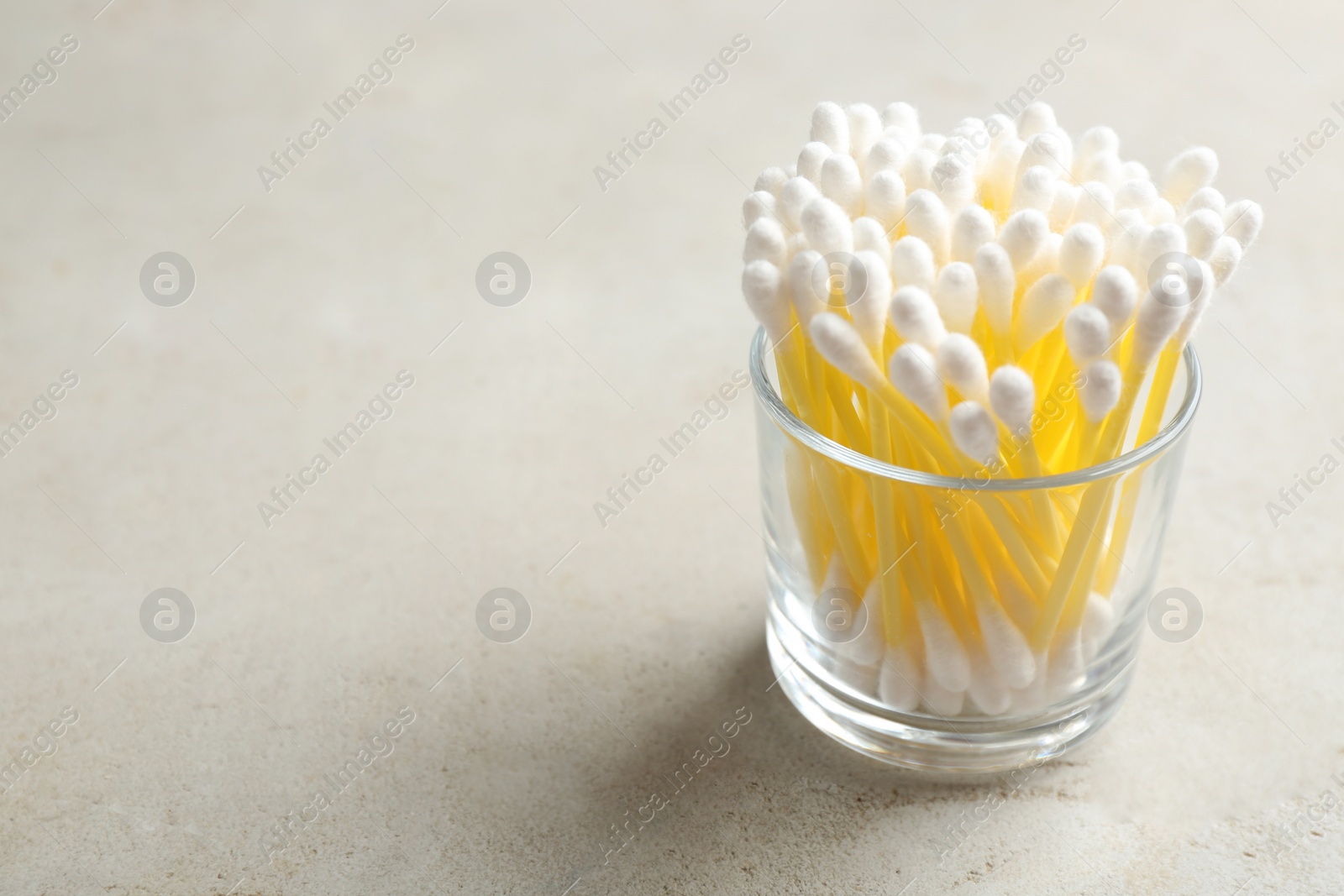 Photo of Glass with cotton swabs on grey background. Space for text