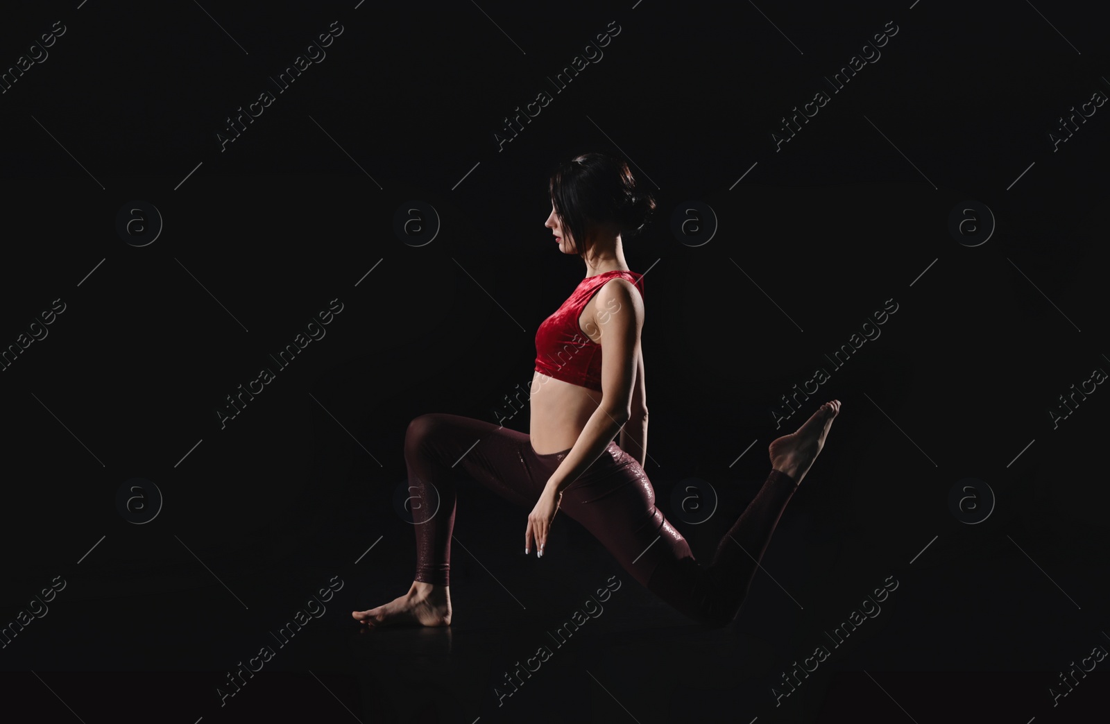 Photo of Young woman performing acrobatic element on stage indoors