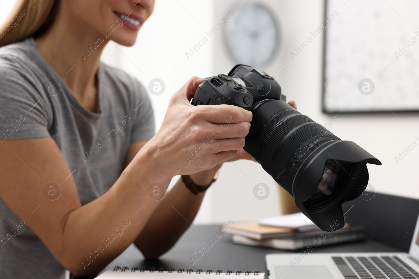 Photo of Professional photographer with digital camera at table in office, closeup