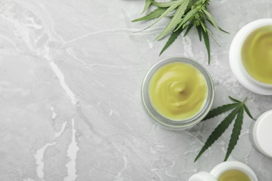 Photo of Jars of hemp cream on grey table, flat lay with space for text. Organic cosmetics