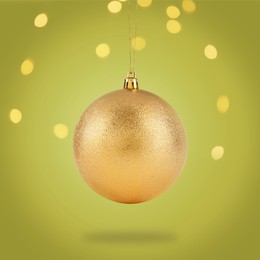 Image of Beautiful golden Christmas ball hanging on color background