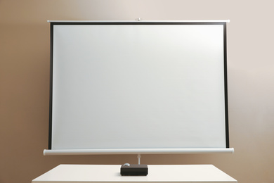 Photo of Video projector and screen near beige wall indoors. Space for design