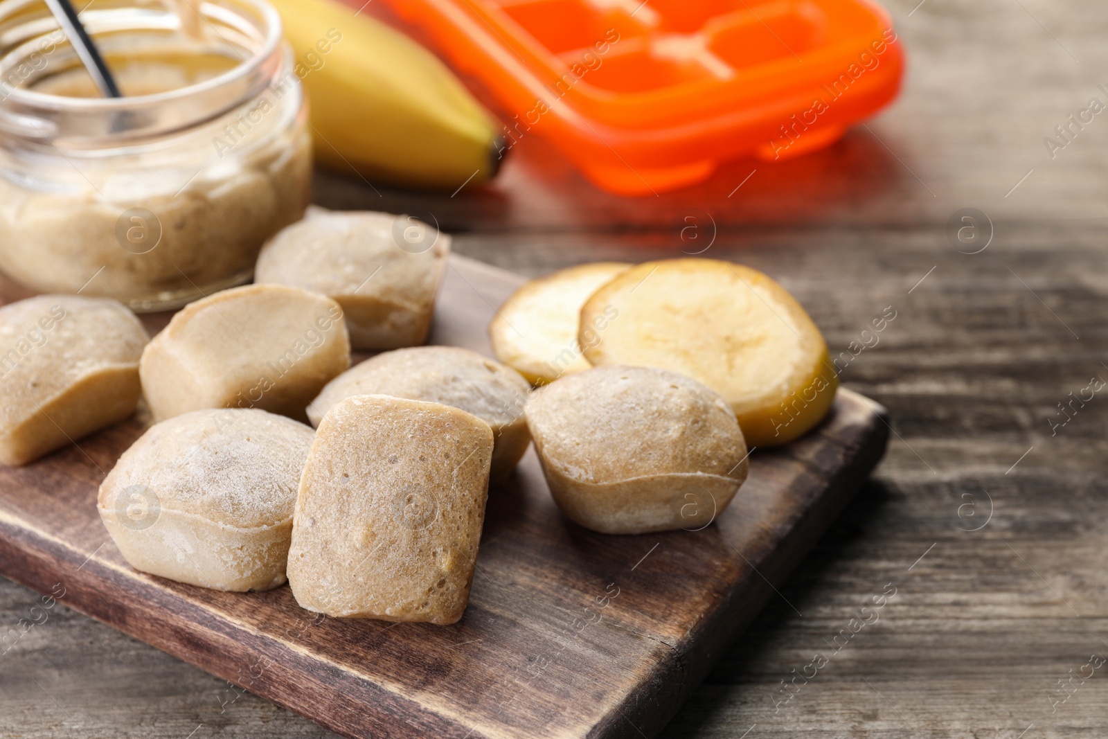 Photo of Frozen banana puree cubes and ingredient on wooden table, closeup